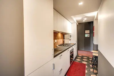 a kitchen with white cabinets and a red rug at Roof top magic Piazza del Popolo in Rome