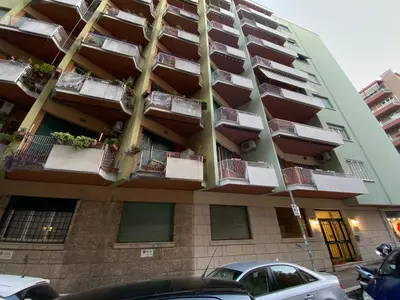 an apartment building with balconies and cars parked in front at FG St Peter's Suites in Rome