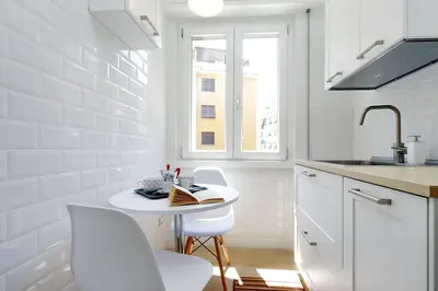 a white kitchen with a small table and white chairs at My Little Holiday in Rome