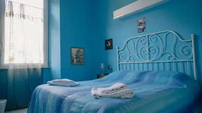 a blue bedroom with a bed with towels on it at Casa Particular 25Rooms in Rome