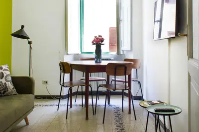 a room with a table with chairs and a vase of flowers at TrastevereHome - San Cosimato View on Trastevere Square in Rome