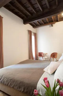 a bedroom with a bed with two chairs and a window at Palazzetto de Lante Appartamento Pinta in Rome