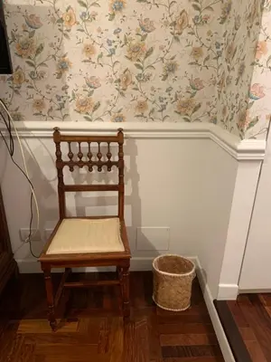 a wooden chair sitting in a room with wallpaper at B&b Querini in Rome