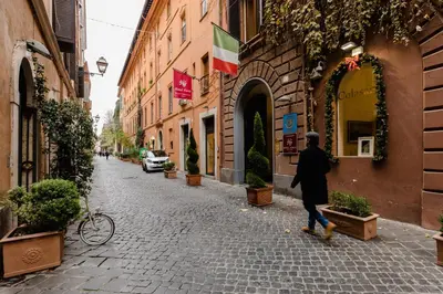 a man walking down a cobblestone street with a flag at A World Aparts - 61 Margutta in Rome