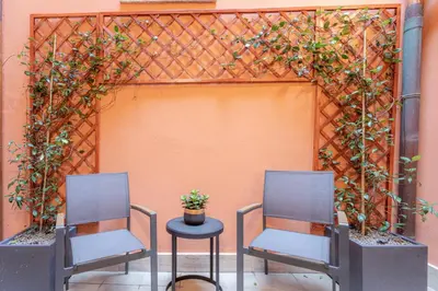 two chairs and a table in front of a fence at Suite Italy Roma in Rome