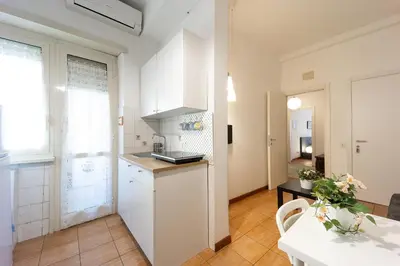 a kitchen with white cabinets and a table in a room at Mirabella Apartment in Rome