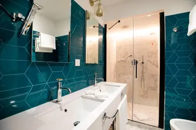 a bathroom with a sink and a shower with blue tiles at Vicario Suites in Rome