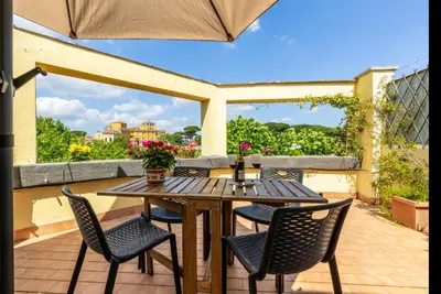 a wooden table and chairs on a patio with an umbrella at Trastevere In Love in Rome
