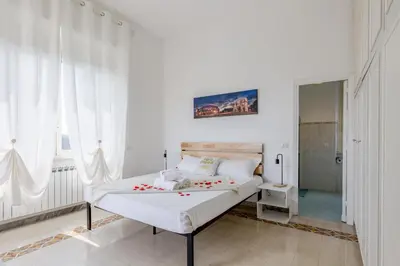 a white bedroom with a bed with red flowers on it at Trastevere In Love in Rome