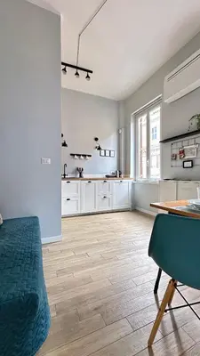 a large kitchen with white cabinets and a wooden floor at Colosseo Apartment 23 in Rome