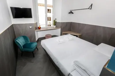 a bedroom with a bed and a chair and a television at Ottaviano Smart Rooms in Rome