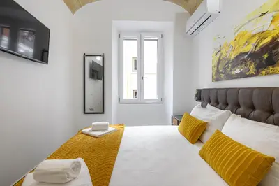 a bedroom with a large white bed with yellow pillows at Industrial-Style Apartment Next To Vatican Metro in Rome