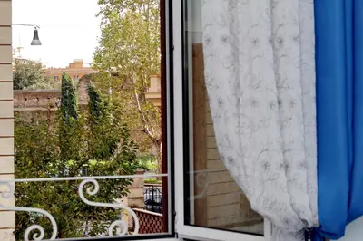 a window with a white curtain and a bench outside at GEMMA DOMUS in Rome