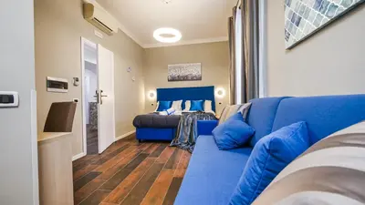 a living room with a blue couch and a bed at Home Suites Giolitti in Rome
