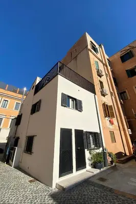 a white building with black doors on a street at Old Town Home Trastevere in Rome