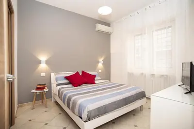 a white bedroom with a bed with red pillows at Cosy Apartment 5 minutes from St Peter in Rome