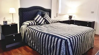 a bedroom with a bed with a striped comforter and two lamps at STEFY ROME APARTMENT in Rome