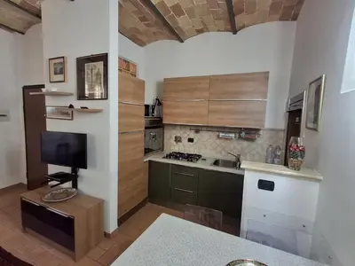 a kitchen with wooden cabinets and a flat screen tv at Elegante appartamento immerso nei Fori Imperiali in Rome