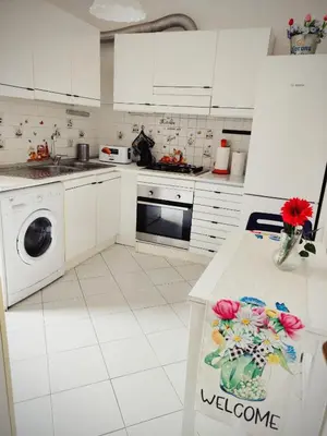 a kitchen with white cabinets and a counter with flowers on it at Tizy & Toto's apartment near Vatican in Rome