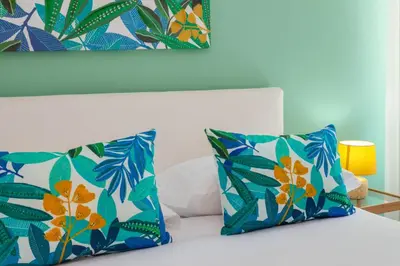 a bedroom with a bed with blue and green pillows at Tizy & Toto's apartment near Vatican in Rome