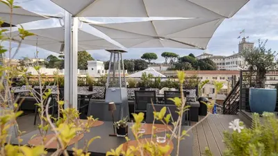 a rooftop patio with tables and white umbrellas at U-Visionary Roma Hotel in Rome