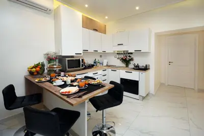 a kitchen with white cabinets and a table with food on it at La Maisonnette Tritone Trevi Apartment Rome in Rome