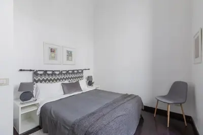 a white bedroom with a bed and a chair at iFlat Colosseum Comfy House in Rome
