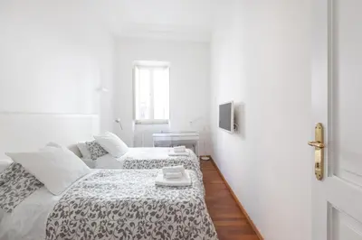 a white bedroom with two beds and a door at Stay In Rome in Rome