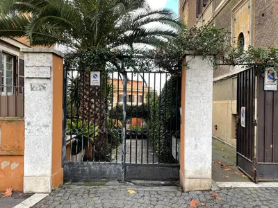 an iron gate with a palm tree behind it at Cosy studio in the greenest corner of Trastevere in Rome