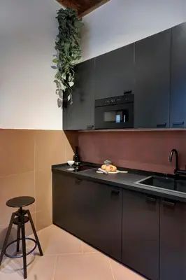 a kitchen with black cabinets and a sink and a stool at Luxury Trevi House in Rome