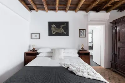 a bedroom with a bed with white sheets and wooden ceilings at Classic and chic apartments in Trastevere in Rome