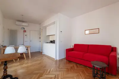a living room with a red couch and a kitchen at Apartment with Terrace in via del Pellegrino - FromHometoRome in Rome