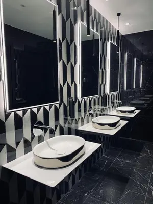a black and white bathroom with four sinks and mirrors at Hotel St Martin by OMNIA hotels in Rome