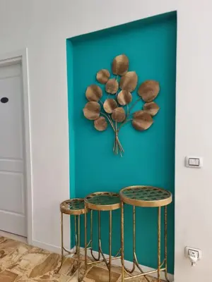 a wall with a clock on a blue wall with two stools at Vatican Fairytale Garden in Rome