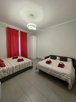 two beds in a room with red curtains at Roman Art Apartment - Metro C to Colosseum in Rome
