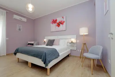 a white bedroom with a bed and a chair at Elegant 3-Bed Apartment 10' Termini Wi-Fi AC in Rome