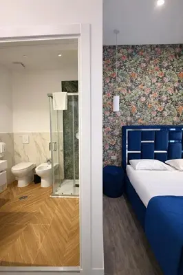 a bedroom with a blue bed and a bathroom at IHH COLLECTION - Eden Luxury Roma in Rome