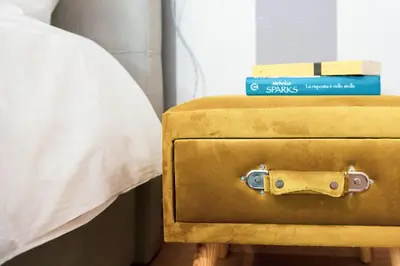 a yellow suitcase sitting next to a bed with two books at Relais Mantellini in Rome