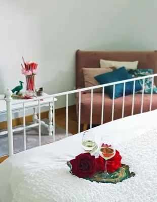 a tray with two glasses of wine and roses on a bed at Glory House Trastevere in Rome