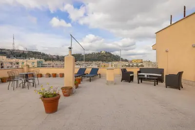 a patio with chairs and tables on a roof at Top Floor Apt with Rooftop Terrace near St. Peter in Rome