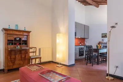 a living room with a table and a kitchen at Three bedrooms in world-famous Via Giulia - FromHometoRome in Rome