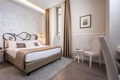 a bedroom with a bed and a desk and a chair at Relais de l'Opera Suites in Rome