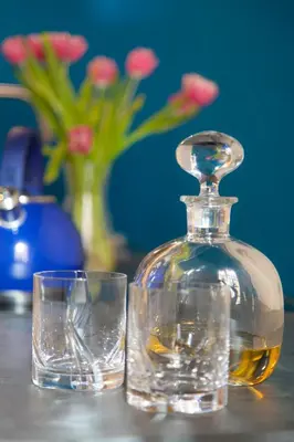 a bottle of whiskey and two glasses on a table at Palazzetto de Lante Appartamento Parione in Rome