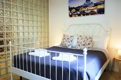 a bedroom with a white bed and a wall of wine bottles at THE ROMAN WAY Museum in Rome