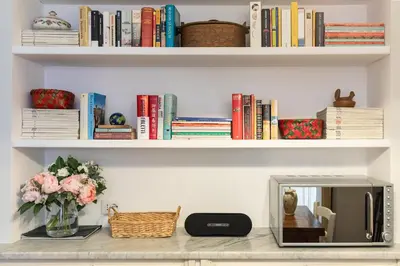 a shelf with books and a vase of flowers and a mirror at Rome As You Feel - Paradiso Apartment in Rome