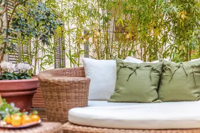 a rattan couch with pillows sitting on a patio at Green Terrace Loft Colosseum in Rome