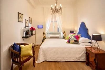 a bedroom with a bed with a chandelier and a chair at Daplace - Flaminia Apartment in Rome