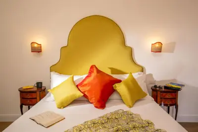 a bed with a yellow headboard and colorful pillows at Daplace - Flaminia Apartment in Rome