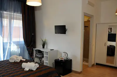 a bedroom with a bed and a desk and a television at Check-Inn Rooms in Rome