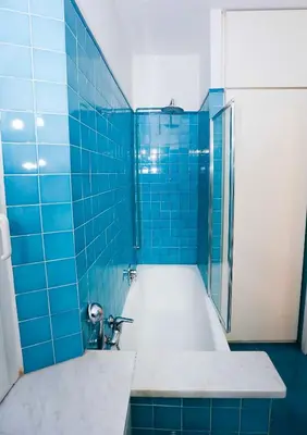 a blue tiled bathroom with a tub and a shower at Lovely Maisonette Trastevere in Rome